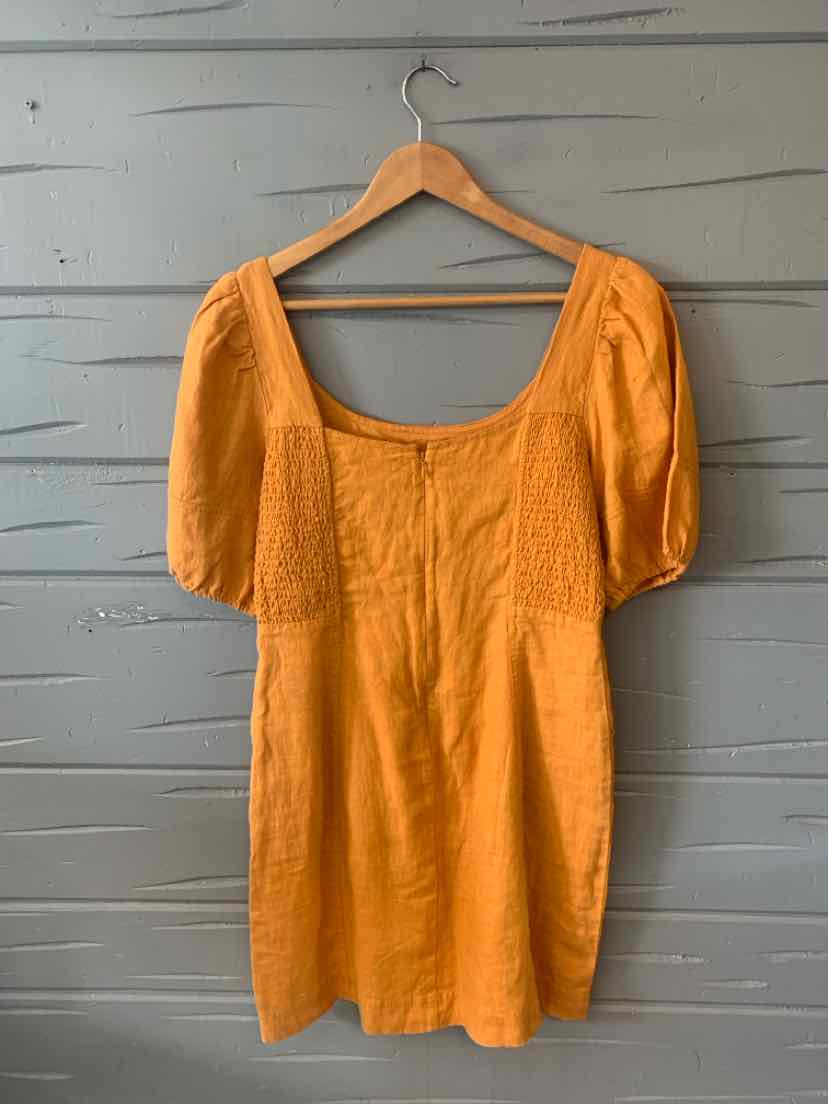 Tan short-sleeve dress with puffed sleeves and square neckline on wooden hanger.