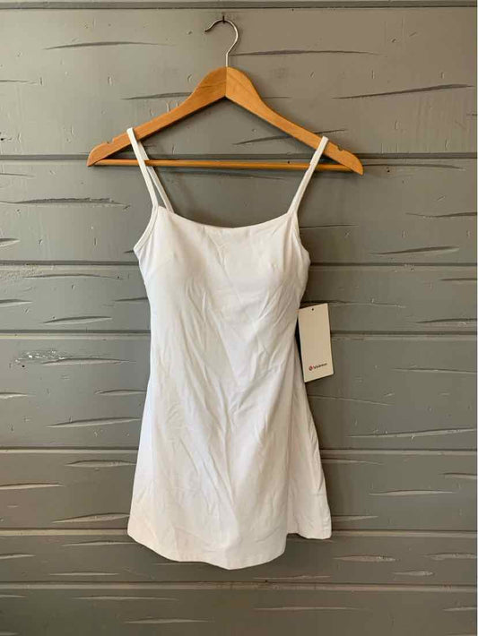 White sleeveless mini dress with thin straps and fitted silhouette on wooden hanger.
