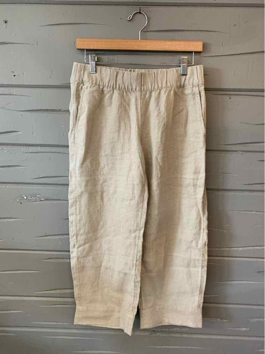 Khaki linen cropped pants with elastic waistband and relaxed fit hanging on wooden hanger.