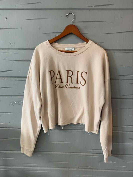 Light beige long-sleeve cropped sweatshirt with "PARIS" and cursive text graphic on front.