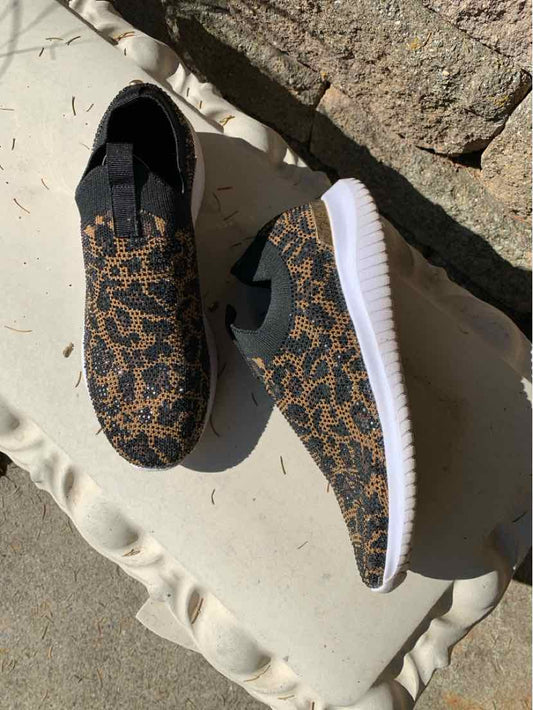 Women's black sneakers with tan animal-print mesh uppers, black laces, and thick white ridged soles.
