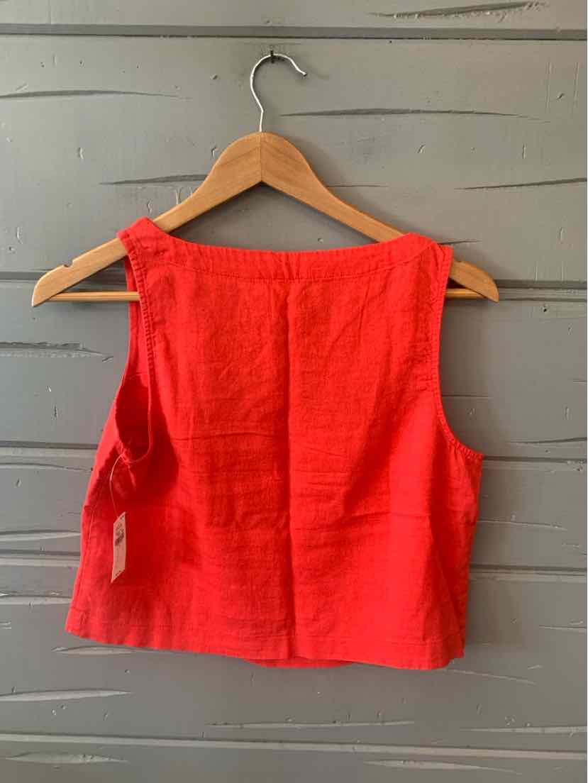Red sleeveless cropped top with square neckline on wooden hanger against gray wall.
