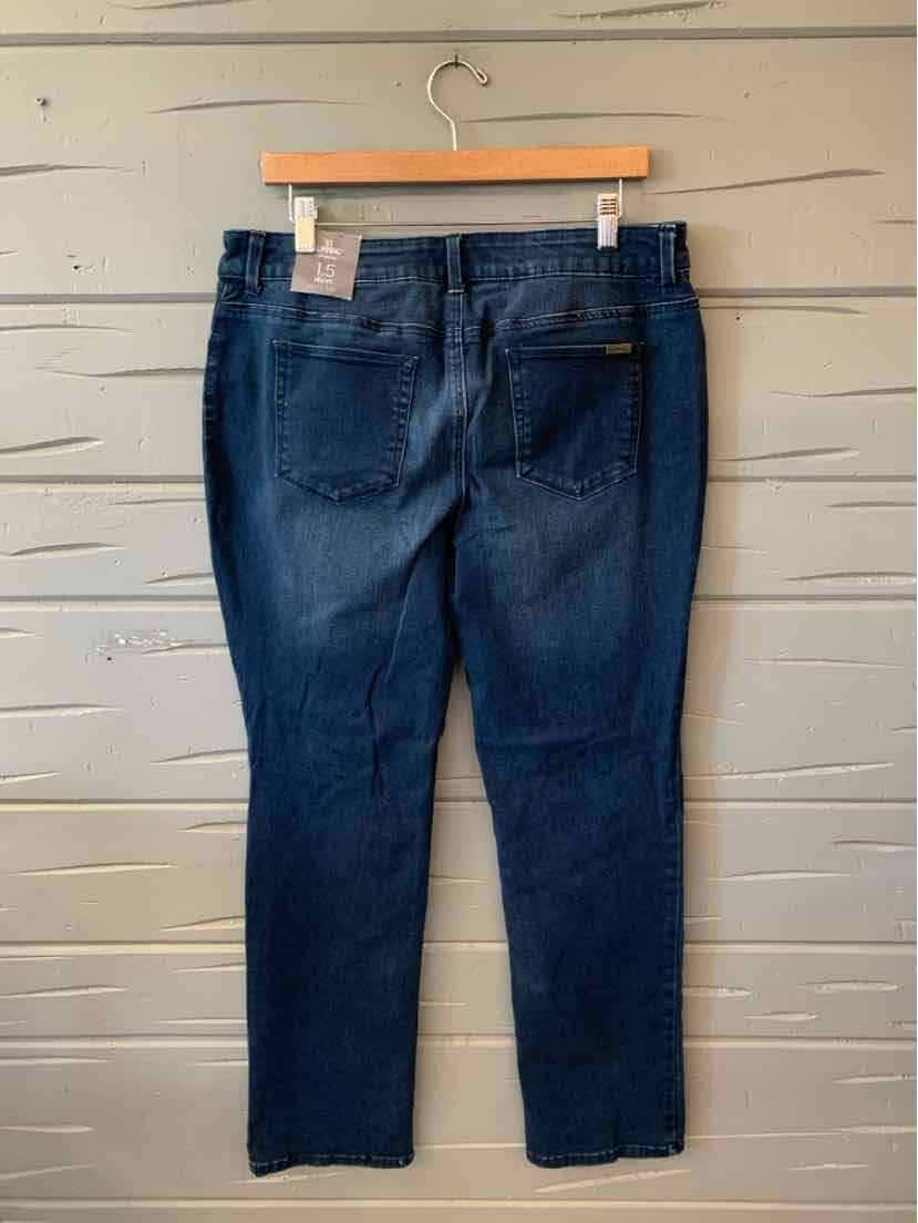 Dark blue solid denim jeans with a slim leg, belt loops, and two back pockets, hanging against a wall.