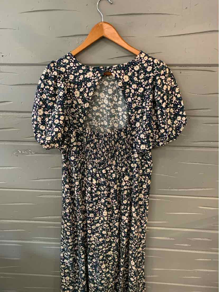 Black floral puff sleeve dress with elastic waist and round neckline on wooden hanger.