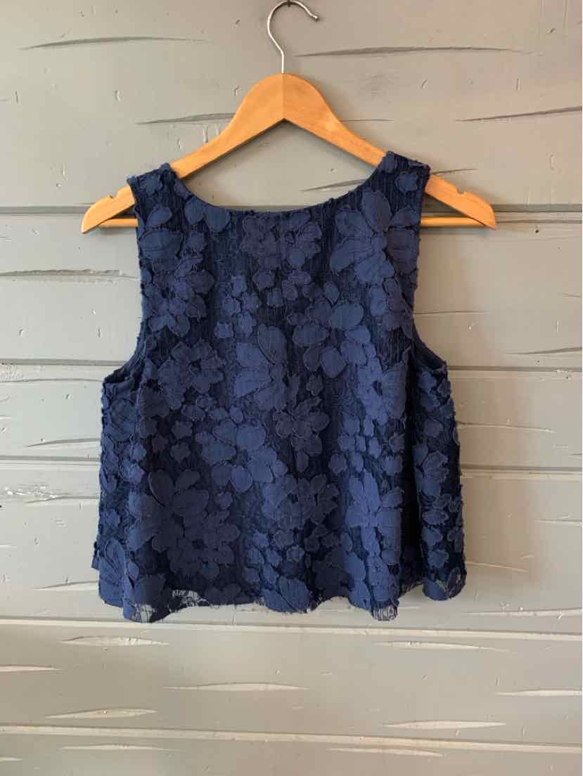Navy blue sleeveless floral lace crop top with a round neckline on a wooden hanger.
