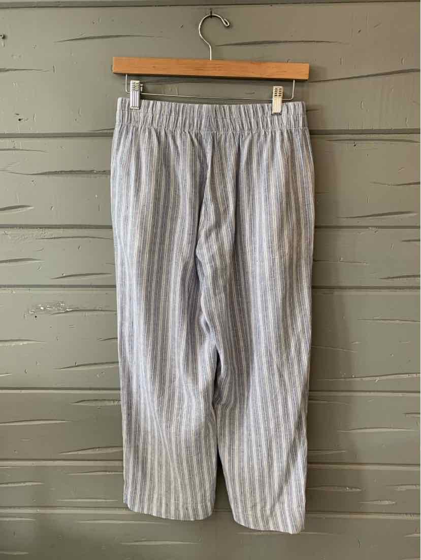 Light blue and white striped casual pants with elastic waistband hanging on wooden hanger.