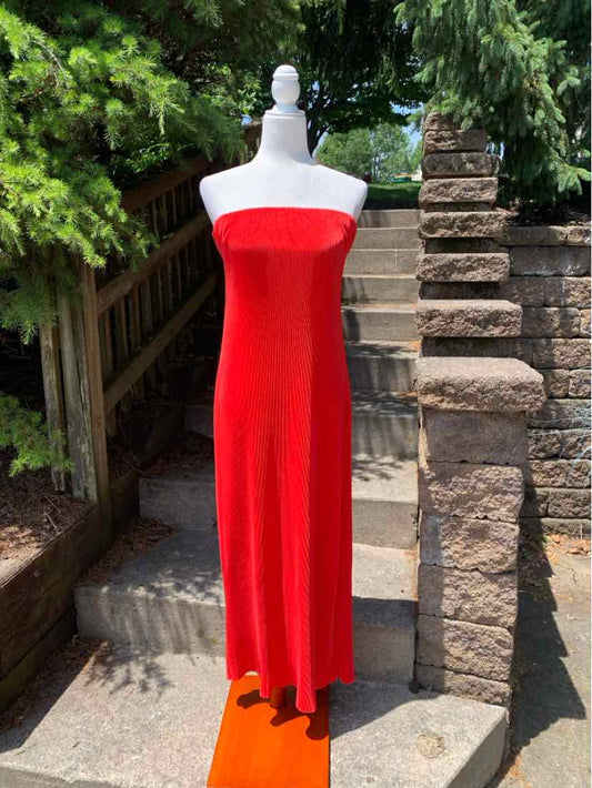 Strapless bright red maxi dress with straight neckline and flowy skirt on white mannequin outdoors.