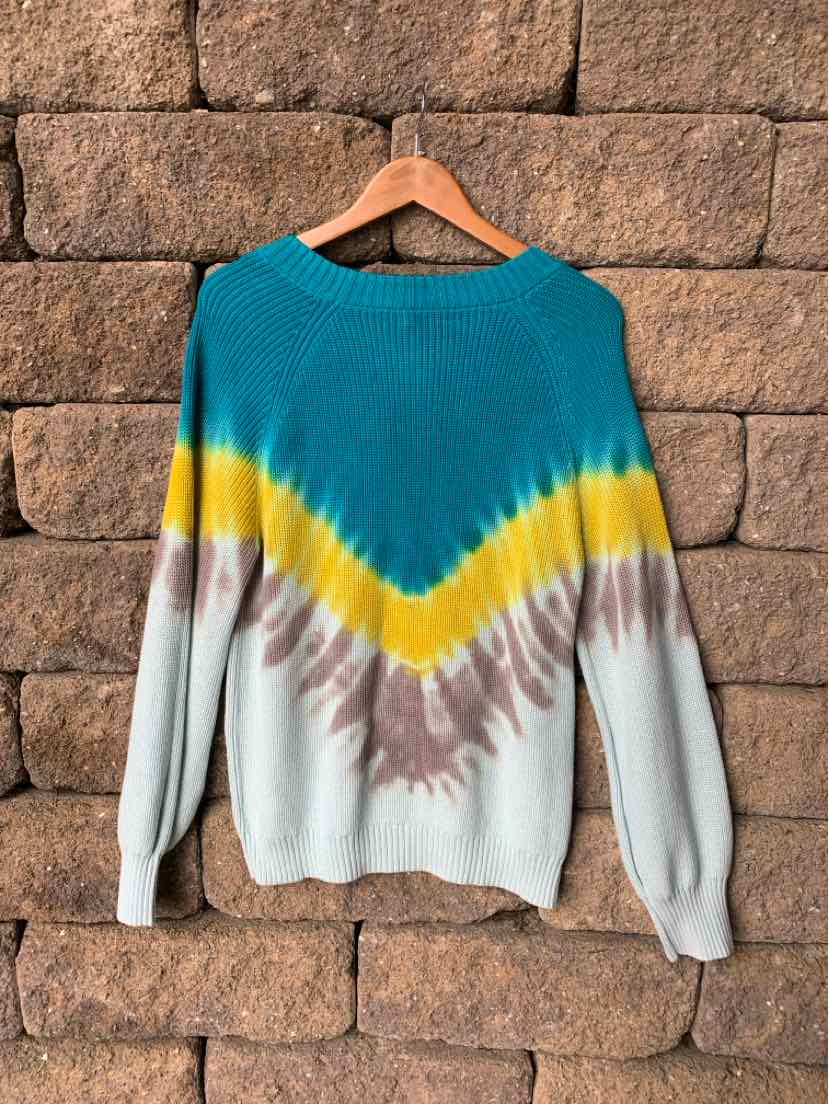 Teal, yellow, and brown tie-dyed knit sweater with long sleeves hanging on wooden hanger.