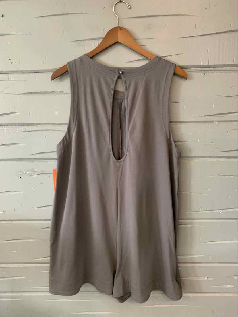 Sleeveless gray top with keyhole back and loose fit on wooden hanger against white wooden wall.