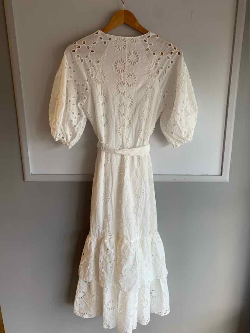 White eyelet midi dress with puff sleeve, cinched waist, and tiered skirt on wooden hanger.