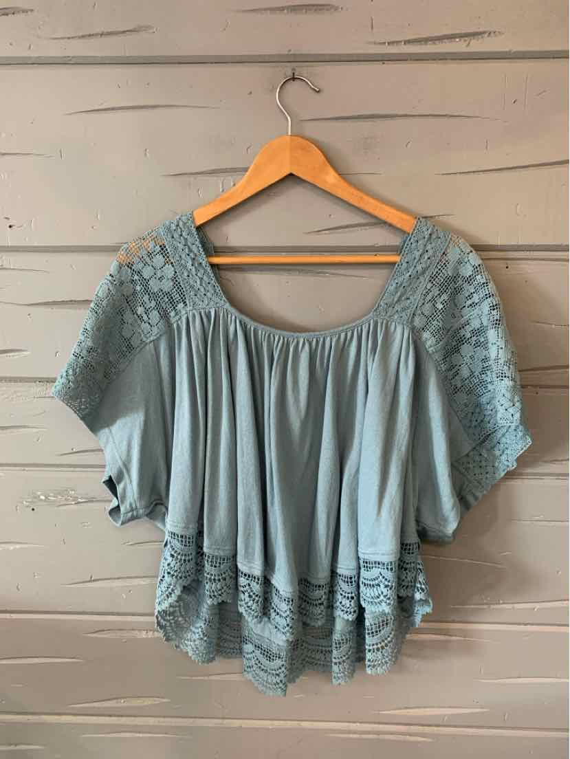 Light blue blouse with loose fit, wide scoop neck, and intricate embroidered detailing on shoulders and hem.
