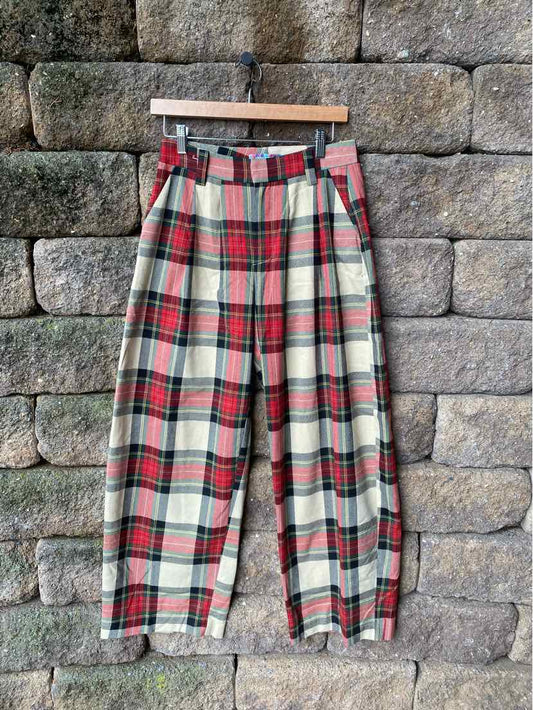 High-waisted plaid pants in red, white, and green with wide legs and a belt at the waist.