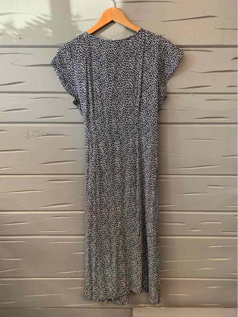 Black and white floral midi dress with short sleeves and gathered waist hanging on wooden hanger.