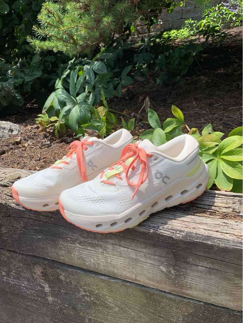White and light gray running sneakers with coral laces and cushioned soles, size 7.5.