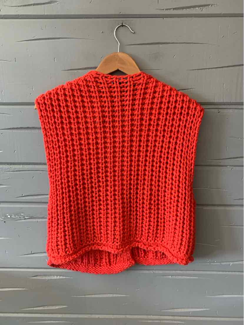 Chunky knit red sleeveless sweater with high-low hem on wooden hanger.