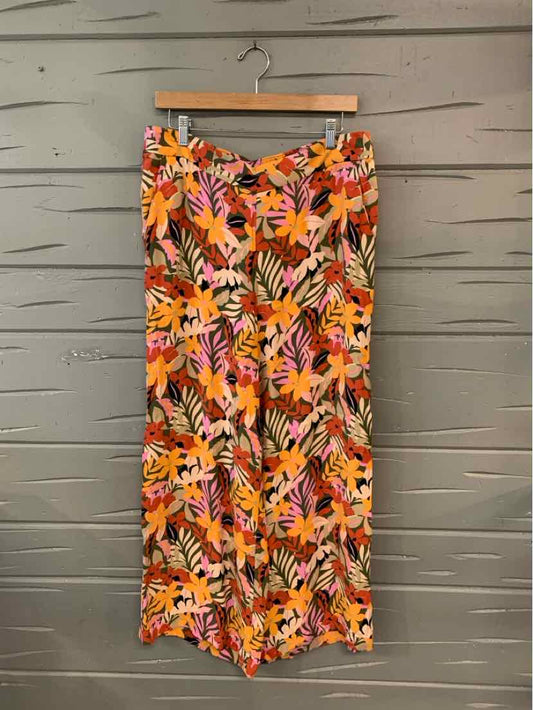 Wide-leg pants with vibrant orange, pink, and beige tropical floral print on lightweight fabric.