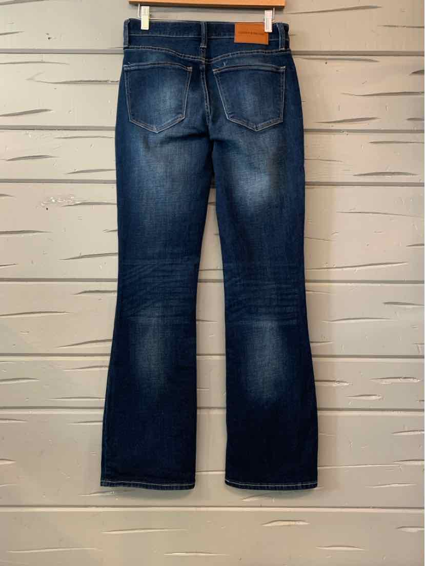 Dark blue Lucky Brand straight-leg jeans with faded thighs, contrast stitching, and back pockets, hanging against a light.