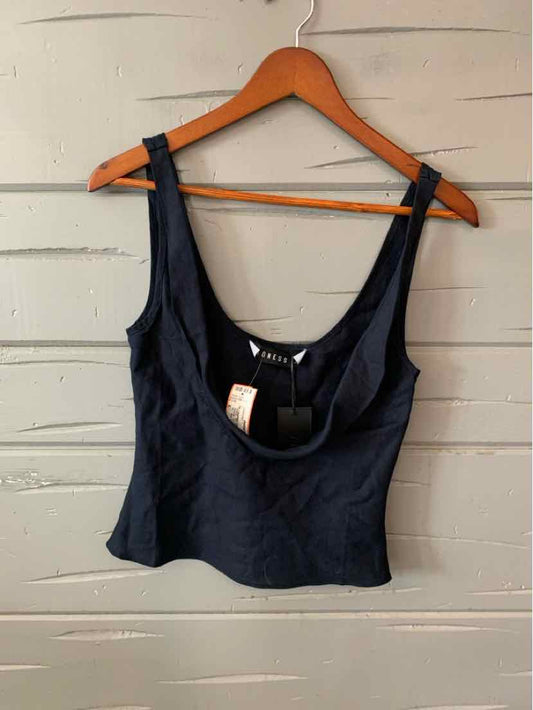 Black cropped tank top with scoop neckline and wide shoulder straps on wooden hanger against gray wooden background.