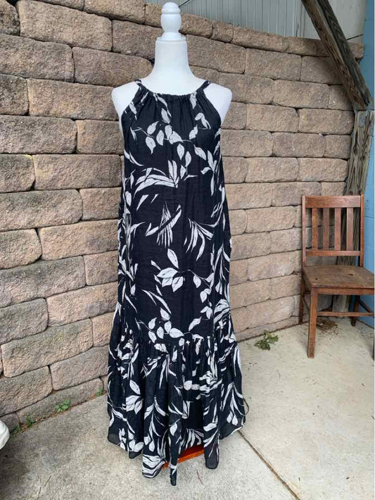 Black sleeveless maxi dress with white floral print and ruffled hem on mannequin.