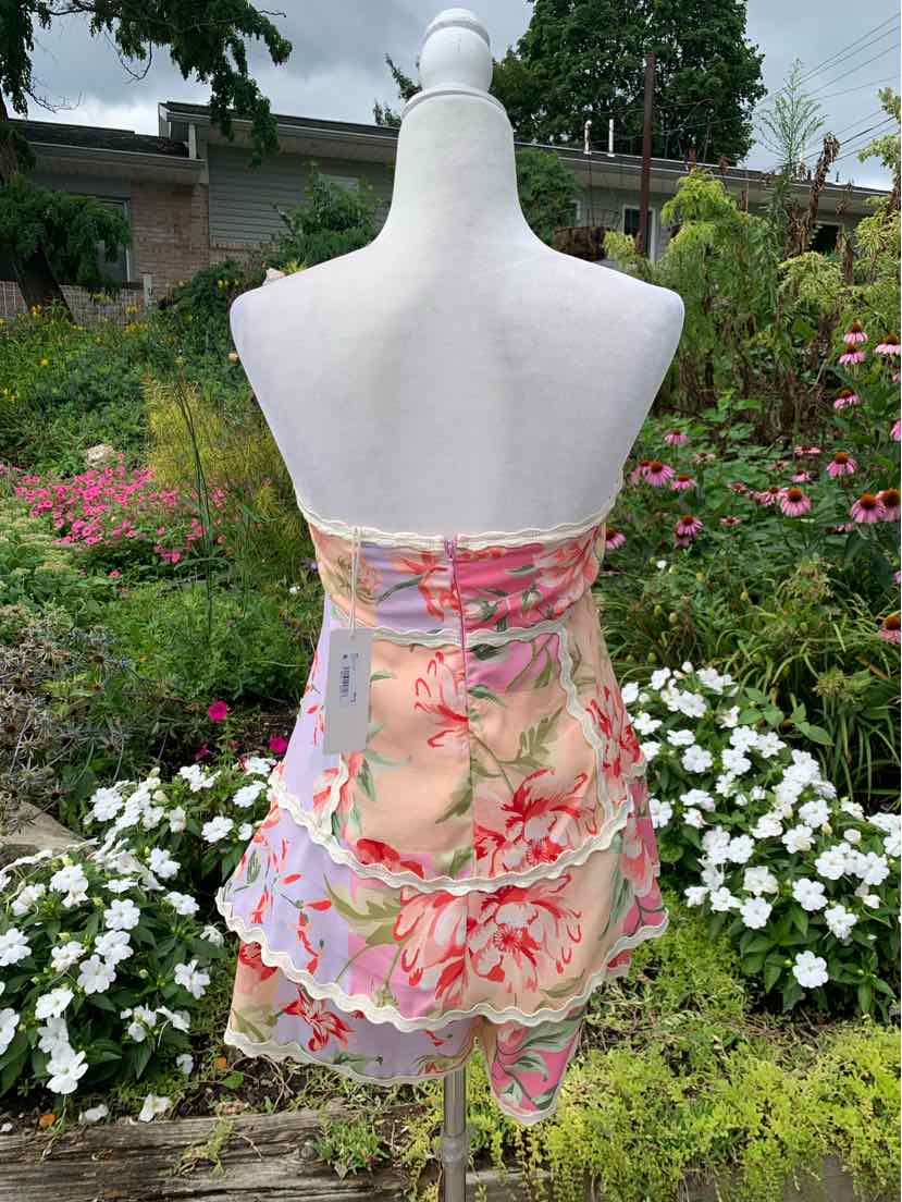 Strapless floral mini dress with pastel pink, peach, and green hues and layered ruffle hem.