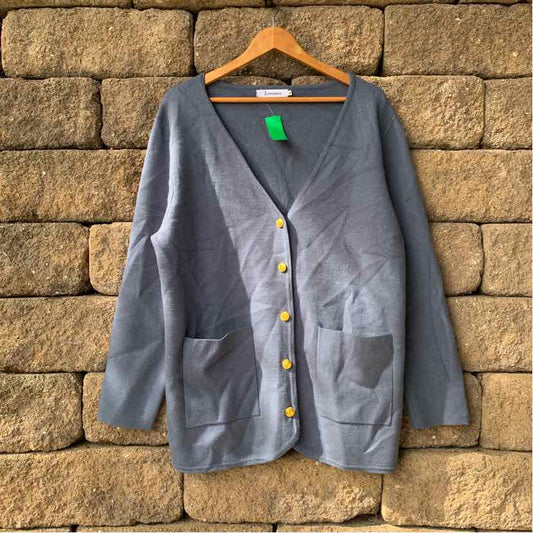 Blue oversized women's casual top with front pockets and yellow buttons on wooden hanger.