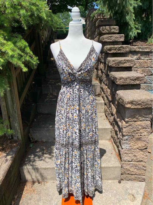 Sleeveless midi dress with a deep V-neck and floral print in muted tones, featuring a tiered skirt and fitted waist.