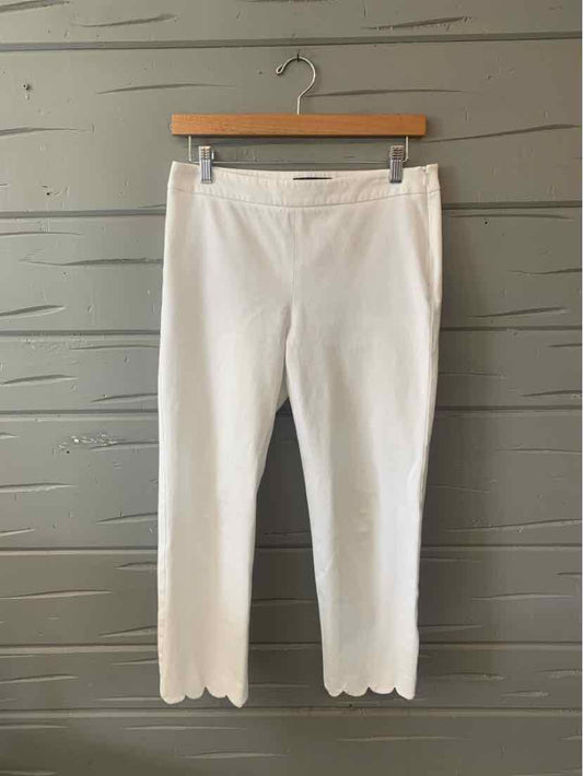 White ankle-length pants with scalloped hems, fitted silhouette, and a smooth waistband.