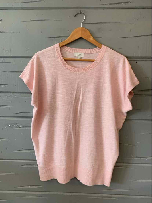 Light pink short-sleeve knit top with round neckline on wooden hanger.