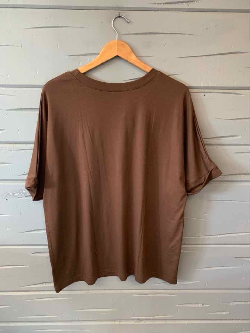 Brown short-sleeve crew neck T-shirt hanging on wooden hanger against gray wall.