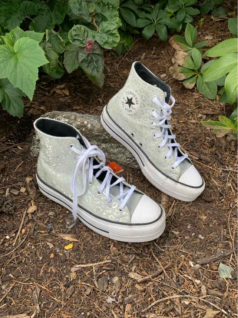 High-top Converse sneaker in beige canvas with black star logo and white rubber sole, white laces.