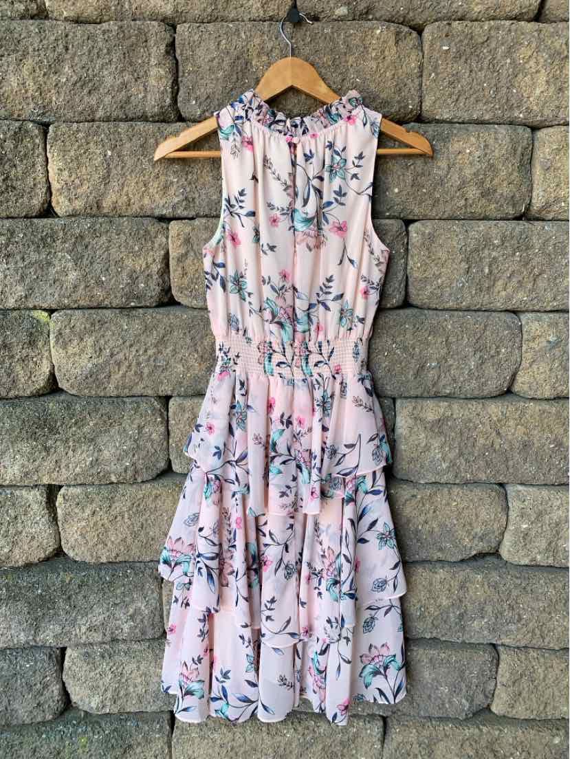 Sleeveless pink midi dress with blue and white floral print, cinched waist, and tiered skirt.