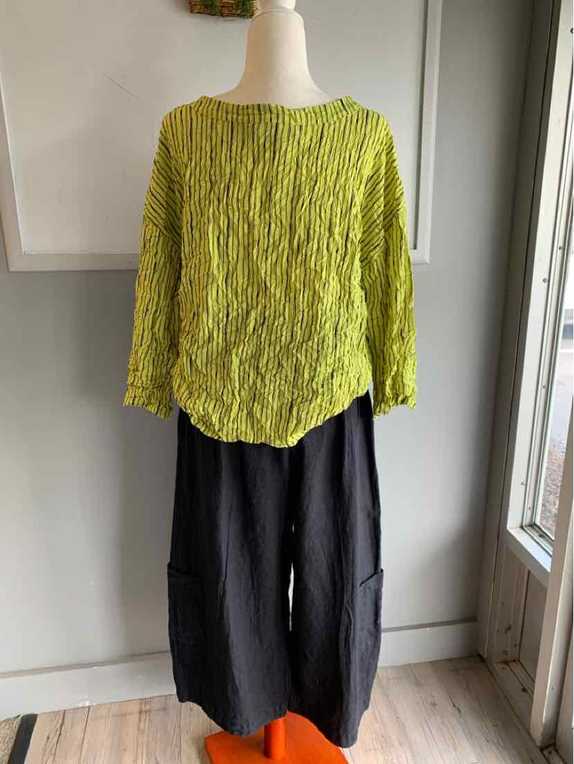Light green crinkled textured long-sleeve top paired with loose black wide-leg pants on a mannequin.