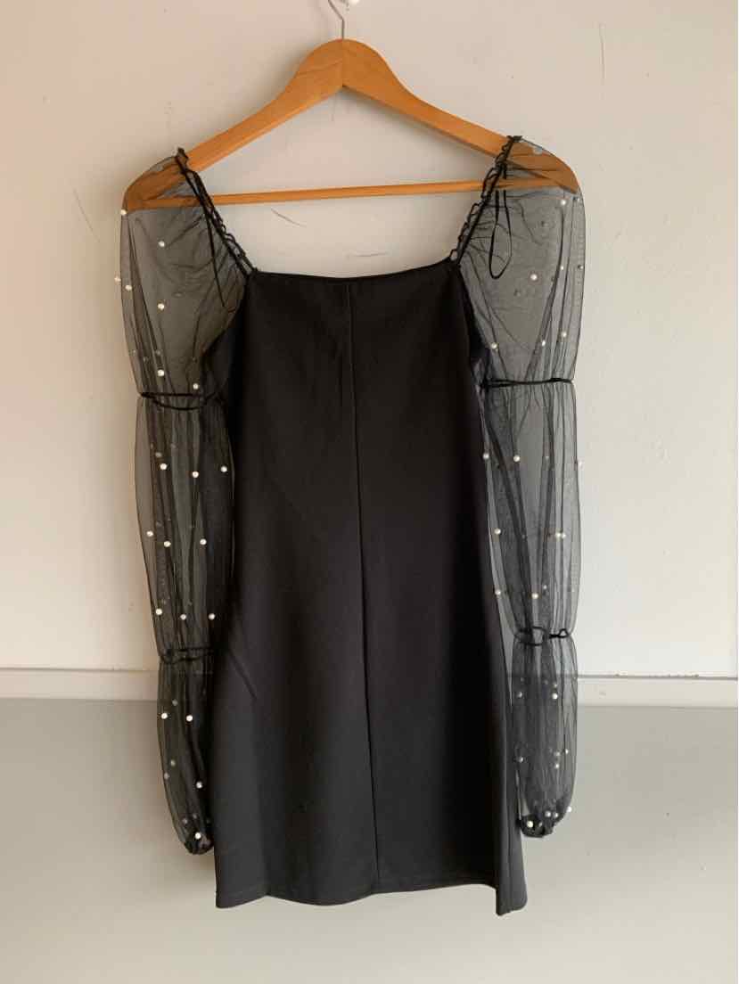 Black mini dress with sheer puff long sleeves adorned with white pearls and thin shoulder straps.