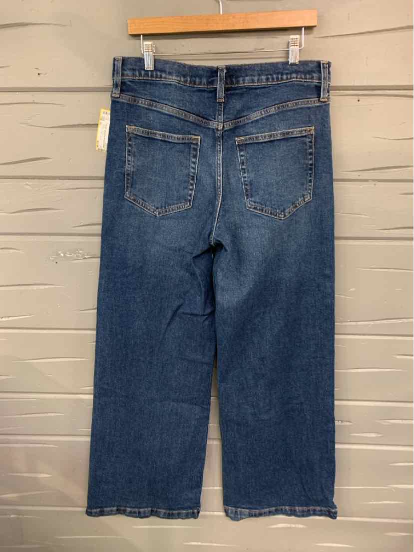 Dark blue denim jeans with straight legs, back patch pockets, and belt loops hanging on wooden hanger.