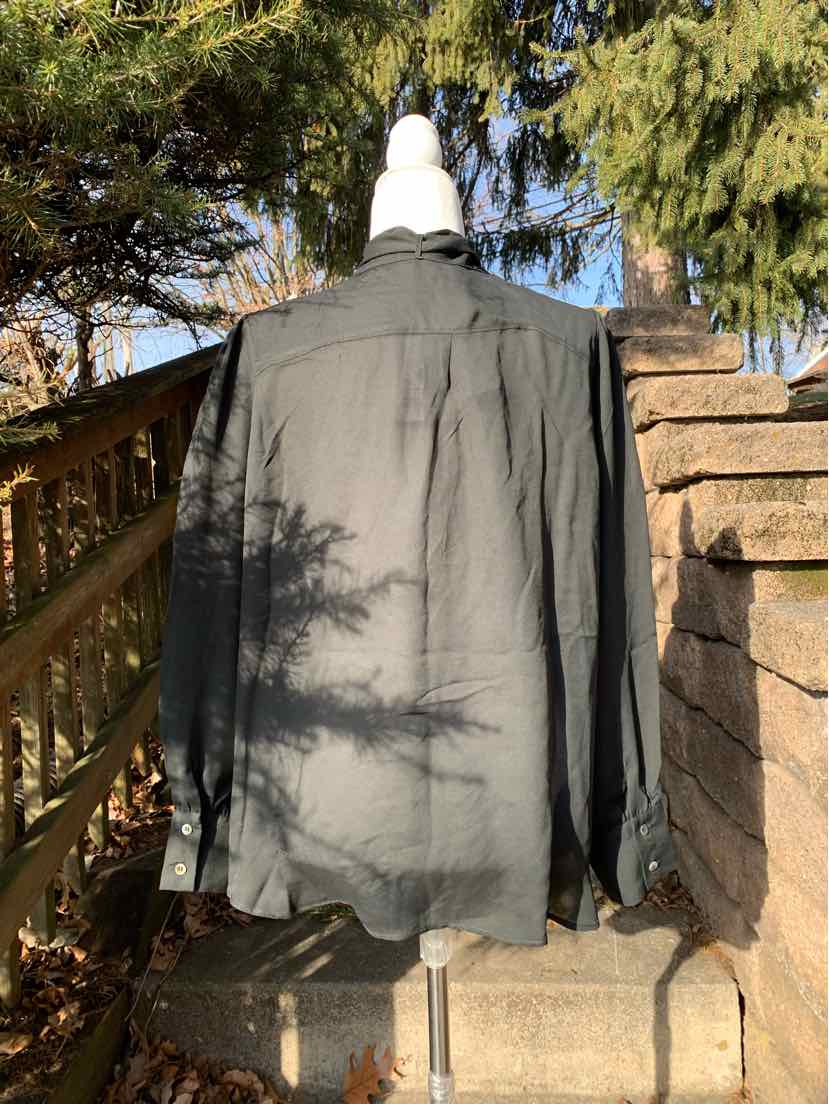Black long-sleeve button-up shirt with collar, displayed on mannequin outside.