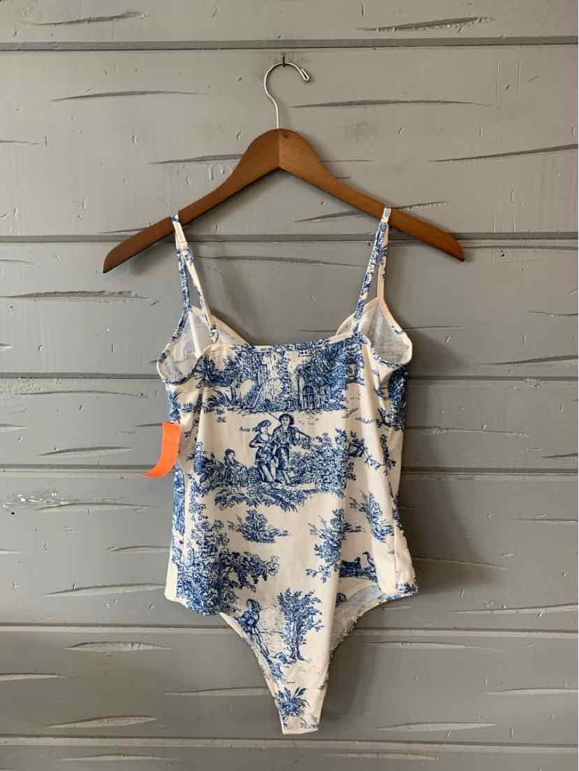 White and blue toile print fitted bodysuit with adjustable spaghetti straps on wooden hanger.