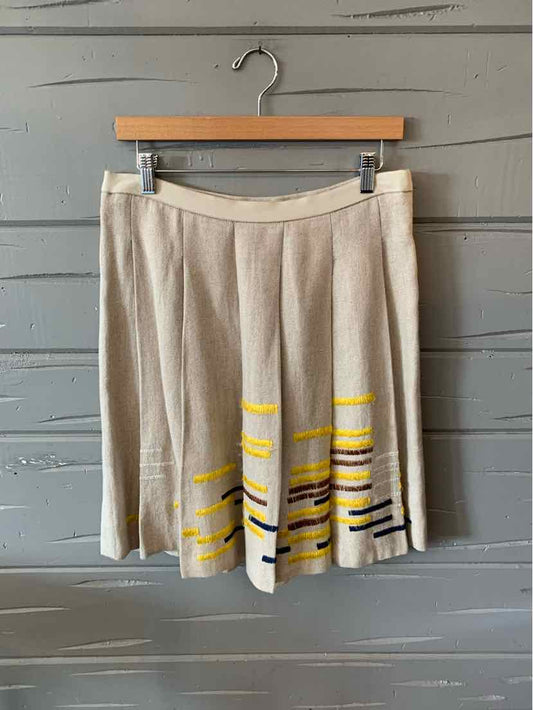 Tan pleated skirt with yellow and black striped accents near the hem, knee-length, size 6.