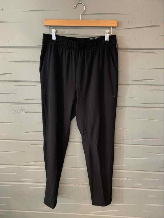 Black slim-fit jogger pants with elastic waistband hanging on wooden hanger.