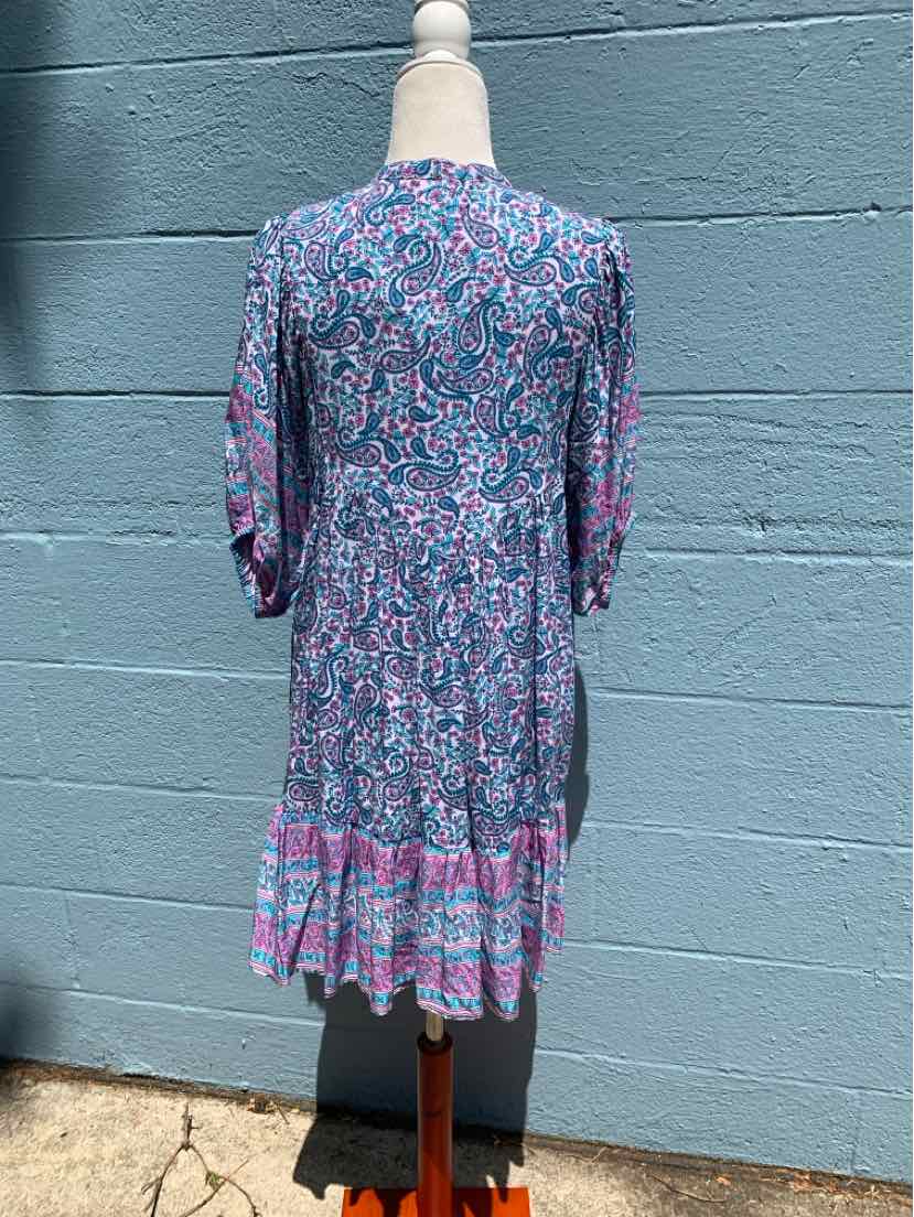 Knee-length dress with long sleeves, featuring a blue base with intricate pink and purple floral patterns and a tiered hem.