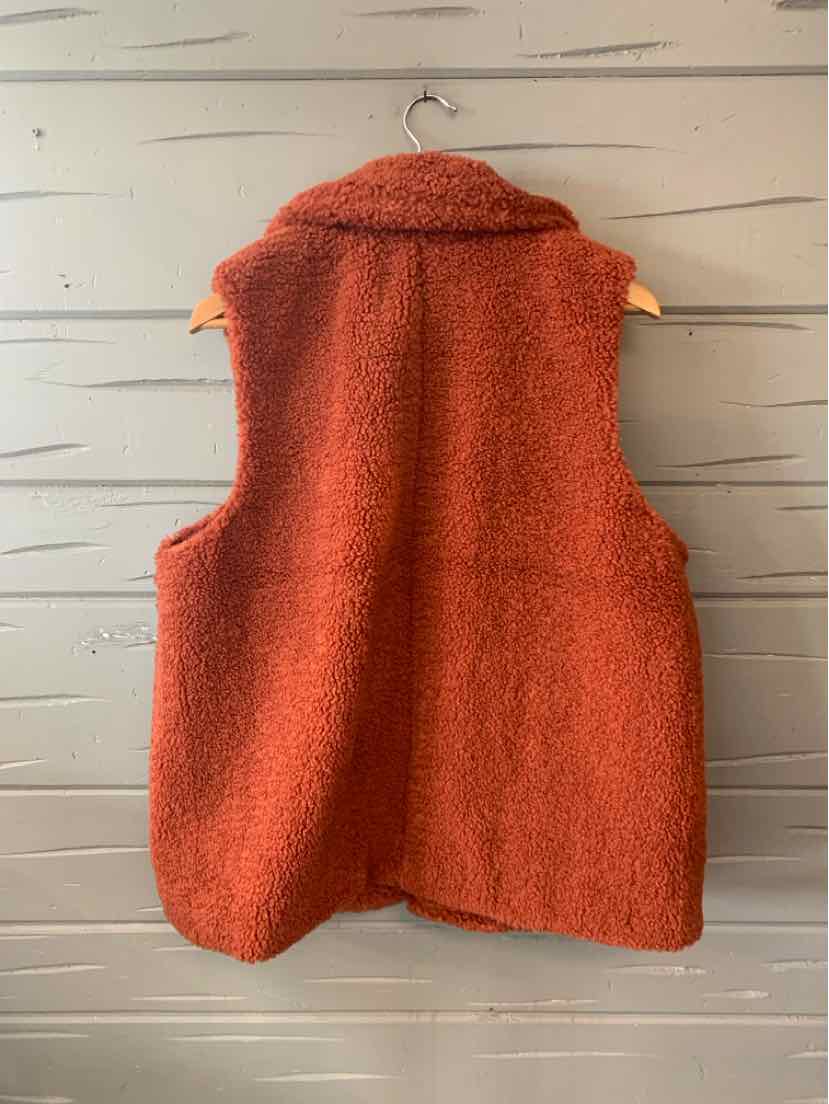 Rust-colored sleeveless sherpa vest with a wide collar and soft textured fabric.