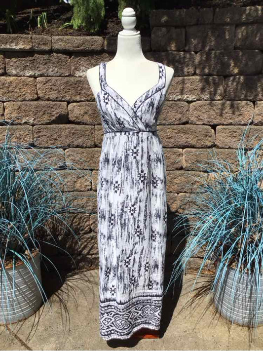 Sleeveless white maxi dress with black abstract pattern and border detail, v-neckline.