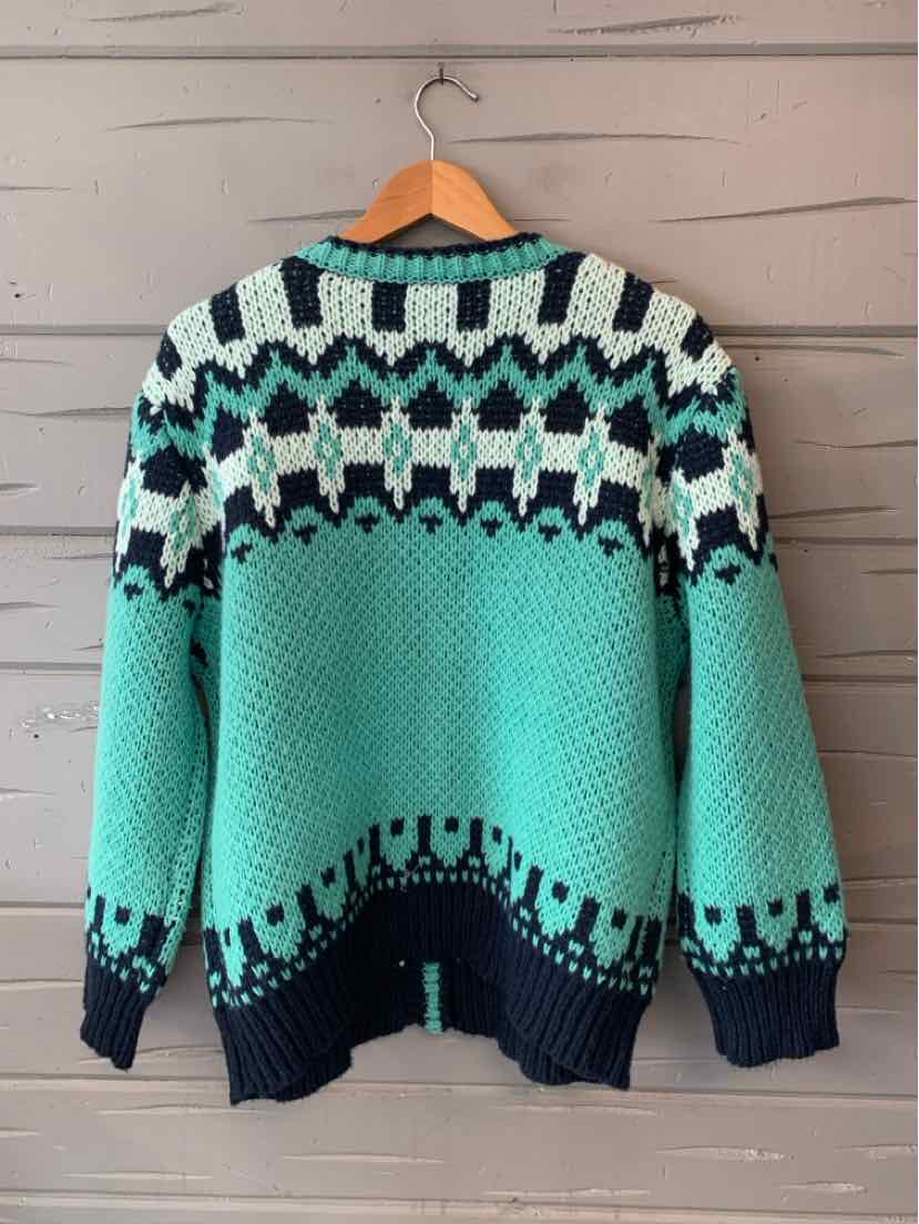Teal knit sweater with a black, white, and mint Fair Isle yoke, patterned cuffs, and hem.