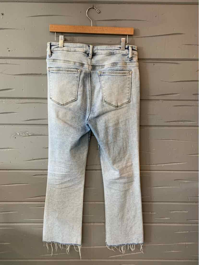 Light blue denim jeans with a straight leg, frayed hems, and back pockets hanging on a wooden hanger.
