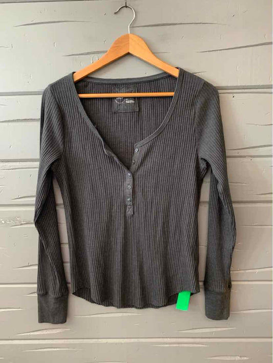 Long-sleeve gray henley shirt with three buttons and fitted cuffs on wooden hanger.