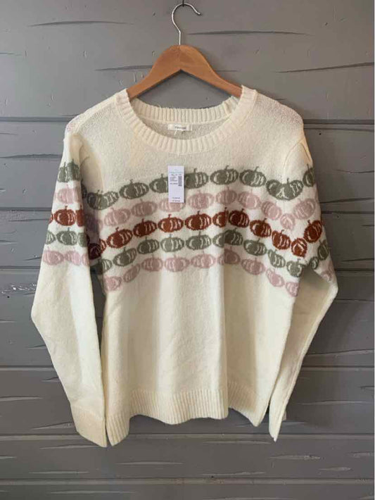 Cream knit sweater with horizontal pumpkin and leaf patterns in orange, brown, and green across chest and sleeves.