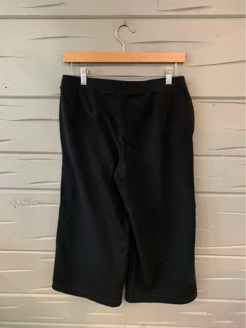 Black mid-length shorts with a straight cut and side pockets hanging on a wooden hanger.