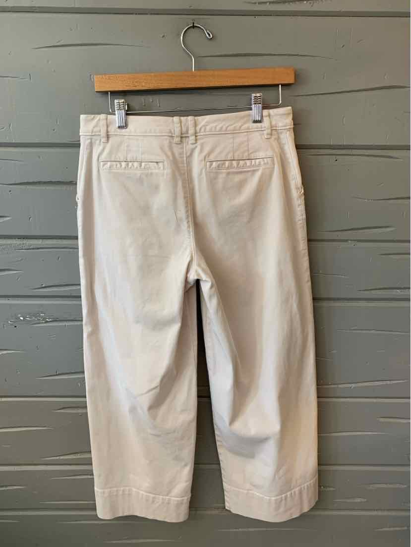 Beige cropped pants in size 6 with back welt pockets and a straight-leg cut hanging on a wooden hanger.