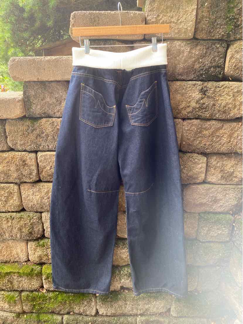 Dark blue wide-leg denim jeans with white elastic waistband and rear patch pockets hanging outdoors.