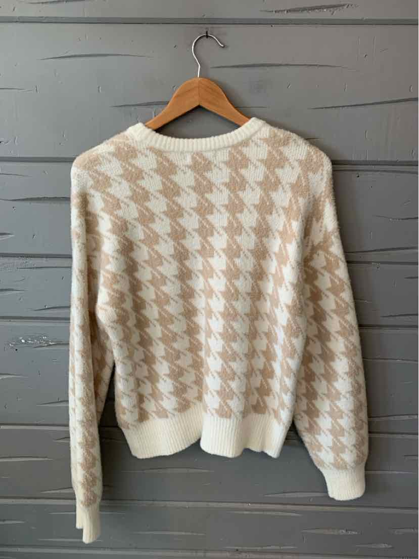 Tan and cream houndstooth knit sweater with ribbed cuffs and hem, size small, hanging on wooden hanger.