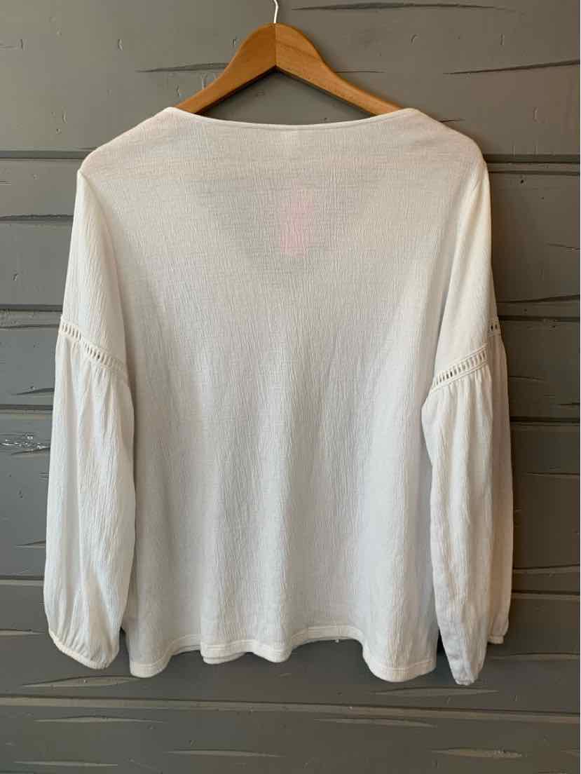 White long-sleeve blouse with gathered puff sleeves hanging on wooden hanger.